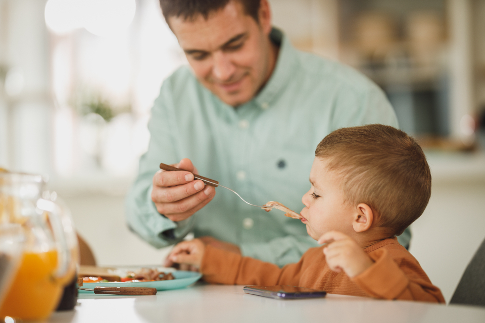 Parent helping a toddler through mealtime