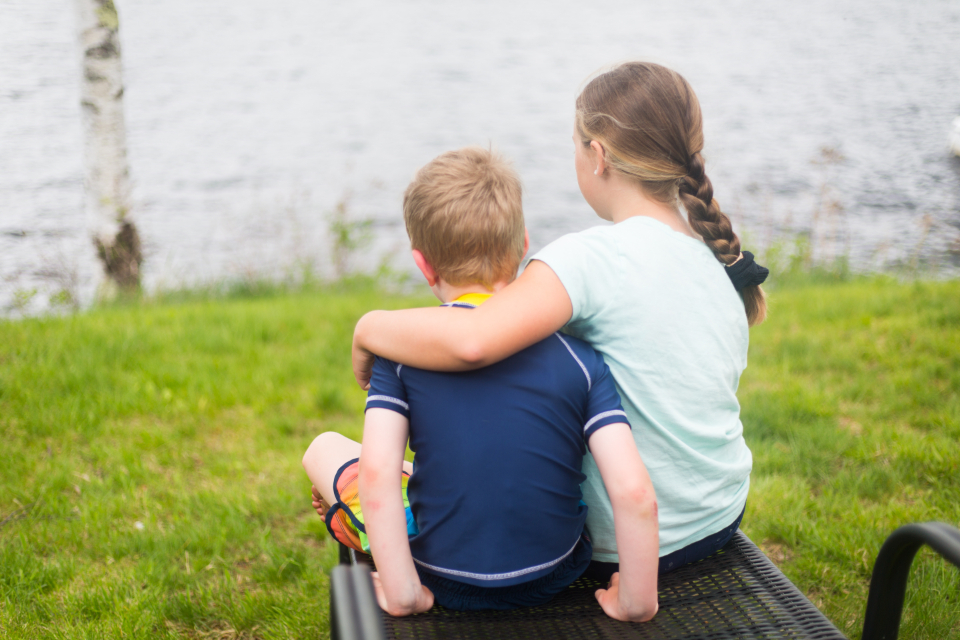 Two siblings sitting together outside after resolving a conflict